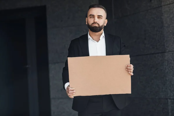 Homem de negócios maduro protestando contra o bloqueio na rua, mostrando sinal de papelão vazio, mockup para o seu texto — Fotografia de Stock