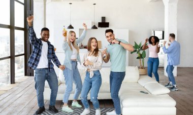 Çok ırklı genç arkadaşlar parti veriyor, dans ediyor ve bira içiyor, evde birlikte eğleniyorlar, panorama