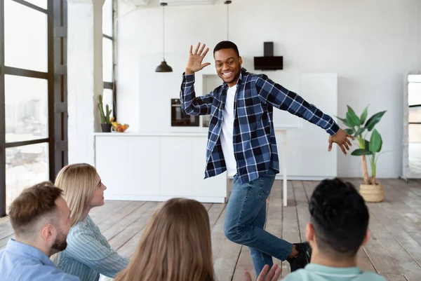 Joyful jonge zwarte man spelen woord raden spel met zijn multiraciale vrienden thuis — Stockfoto