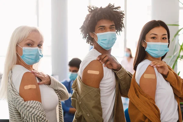 Diversas personas que muestran brazo vacunado con vendaje adhesivo en la clínica —  Fotos de Stock