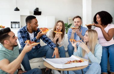 Neşeli çok ırklı arkadaşlar ev partisi yapıyorlar, evde pizza yiyorlar, konuşuyorlar, gülüyorlar, birlikte vakit geçiriyorlar.