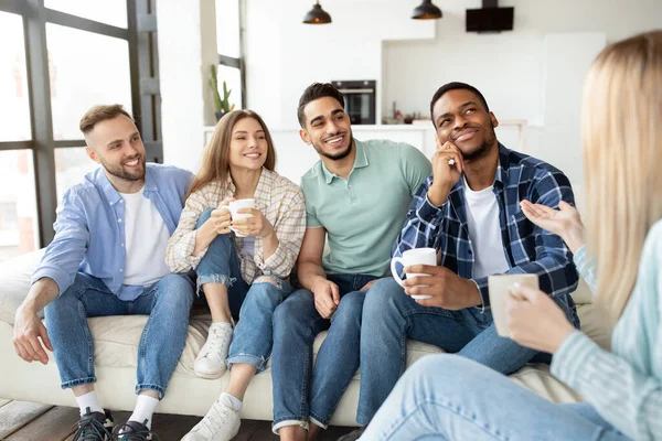 Jeunes amis multiethniques appréciant la conversation, boire du thé ou du café à la maison — Photo
