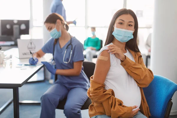 Mujer asiática embarazada feliz mostrando la mano con yeso después de la vacuna — Foto de Stock