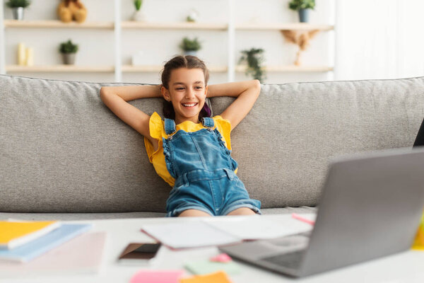 Девушка сидит за столом, с помощью ноутбука, смотрит видео