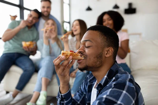 Menő fekete srác eszik pizza hazai party a többnemzetiségű barátaival, másolás helyet — Stock Fotó