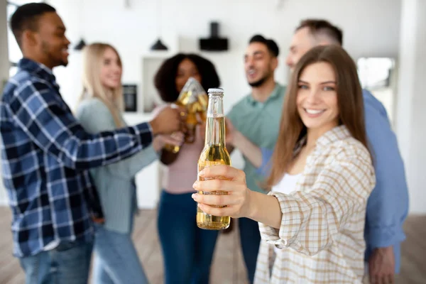 Kafkasyalı genç bir kadın ve çok ırklı arkadaşları bira şişeleriyle kadeh kaldırıyor, evde bir şey kutluyor, yakın plan — Stok fotoğraf