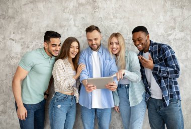 Bir grup bin yıllık öğrenci birlikte tablet kullanıyor, çevrimiçi iletişim kuruyor, internette geziniyor, uzaktan öğrenim görüyor.