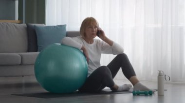 Son sınıf öğrencisi telefonda konuşuyor. Evde Fitness Balosu 'yla oturuyor.