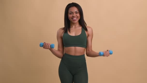 Afroamericana dama haciendo ejercicio con sombrillas de pie sobre fondo beige — Vídeos de Stock
