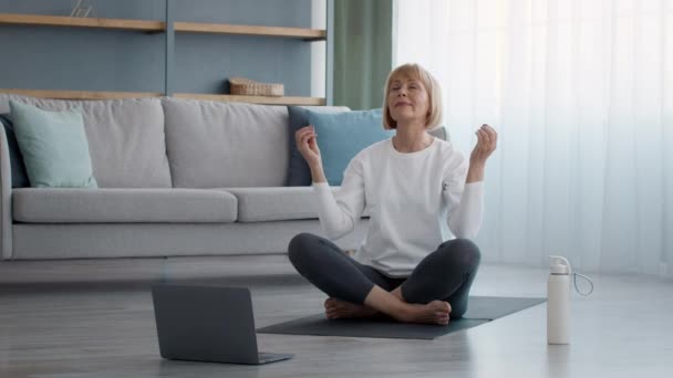 Señora mayor meditando en el ordenador portátil con los ojos cerrados en casa — Vídeos de Stock