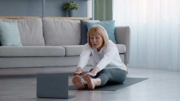 Seniorin am Laptop: Berührende Zehen zu Hause ausstrecken — Stockvideo