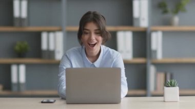 Şirket ödülü. Genç bayan ofis çalışanı işyerinde oturuyor, e-posta alıyor ve okuyor.