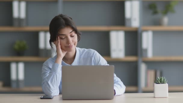 Młoda kobieta kierownik biura siedzi w miejscu pracy i surfingu internetowego na laptopie, czuje się nudno z pracy, zwolnione tempo — Wideo stockowe