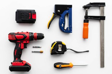 Beyaz arka planda çeşitli bina araçları, üst manzara. Elektrikli matkap, cetvel, kıskaç, tornavida, düz konum