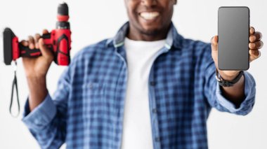 Afrikalı Amerikalı tamirci mobil uygulama, servis veya web sitesi sunuyor, kameraya boş akıllı telefon ekranı gösteriyor