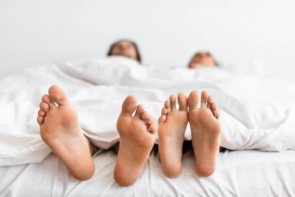 Coppie piedi sotto coperta mentre dormono in camera da letto, Avvicinamento — Foto Stock