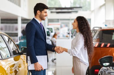 Satış asistanı. Güzel esmer bayanı selamlıyor.