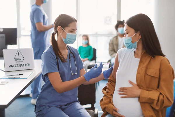 Doktor dělat koronavirus vakcína injekce těhotné asijské dámě — Stock fotografie