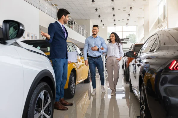 Arabische man sales assistent begeleiden jonge familie door showroom — Stockfoto