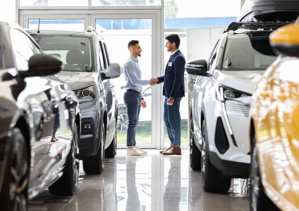 Rico médio-oriental homem tremendo vendas gerente mão no auto showroom — Fotografia de Stock