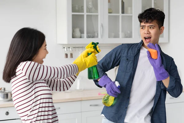 Gelukkig aziatisch paar spatten naar elkaar met schoonmaken sprays — Stockfoto