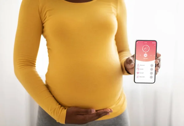 Вагітна жінка показує мобільний додаток для вагітності — стокове фото