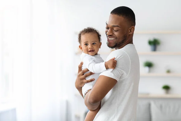Felicidad de la paternidad. Joven papá negro con pequeño bebé en las manos —  Fotos de Stock