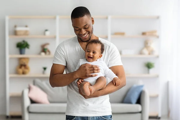 家族と親の概念。幸せなアフリカ系アメリカ人の父親がかわいい笑い幼児の赤ちゃんを保持 — ストック写真