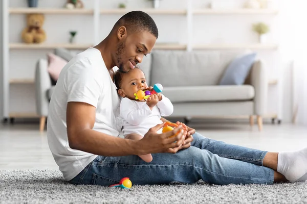 Tempo de paternidade. Amoroso jovem pai afro-americano brincando com bebê infantil em casa — Fotografia de Stock