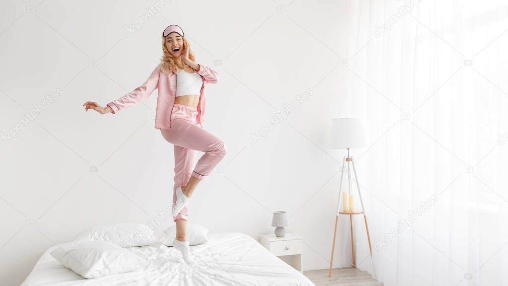 Woman in pink pajamas in white bedroom interior