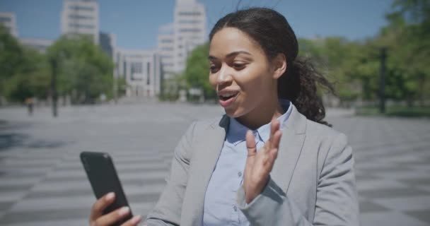 Çevrimiçi iş görüşmeleri. Genç Afro-Amerikalı bir kadının açık hava portresi telefon aracılığıyla ortaklarla görüntülü konuşma. — Stok video