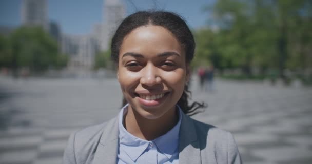 Zoom in portudeの若い幸せなアフリカ系アメリカ人ビジネス女性身に着けている正式なスーツ笑顔へカメラ — ストック動画