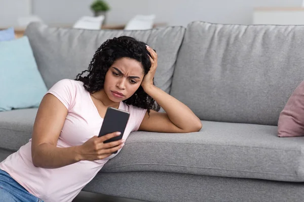 Жінка засмучена після читання поганого повідомлення по телефону вдома — стокове фото