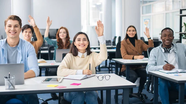 Retrato de diversos estudiantes levantando las manos en el aula — Foto de Stock