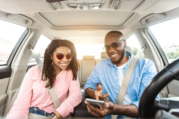 Feliz pareja negra conduciendo coche y usando el teléfono celular —  Fotos de Stock