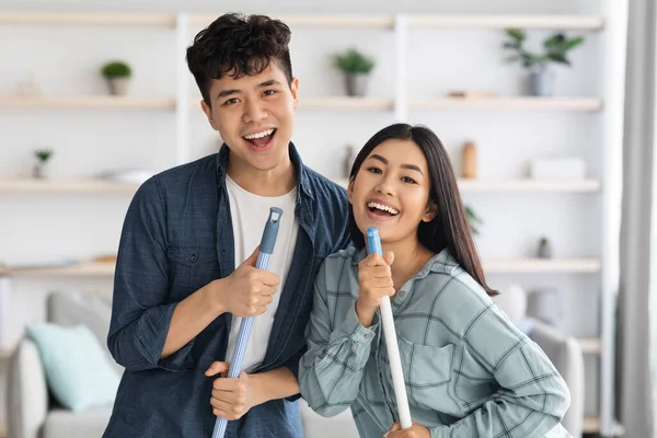 Closeup of positive asian lovers having fun while cleaning apartment — Stock Photo, Image