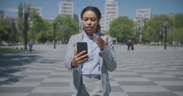 Joven mujer de negocios afroamericana seria que va a trabajar y videoconferencia con socios, siga el disparo — Vídeos de Stock