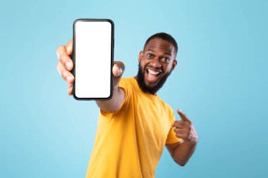 Mobil uygulama reklamı. Heyecanlı siyah adam akıllı telefonu boş ekranla işaret ediyor, maket. Reklam veya web sitesi için boşluk