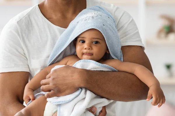 Förtjusande svart spädbarn i handduk Avslappnande i fäder armar efter bad — Stockfoto