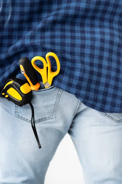 Reparateur concept. Meetlint, schroevendraaier en schaar in broekzak van mannelijke jeans, close-up, gewas — Stockfoto