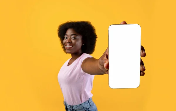 Gelukkig Afrikaans amerikaanse vrouw demonstreren smartphone met groot leeg scherm, tonen vrije ruimte, gele achtergrond — Stockfoto