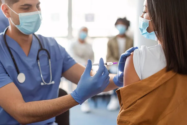 Asijské ženy přijímající koronavirus vakcína injekce sedí s lékařem Indoor — Stock fotografie