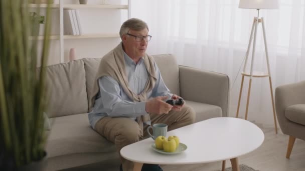 Hobby en cyberactiviteit voor senioren. grijsharige volwassen man spelen video games met joystick en winnen — Stockvideo