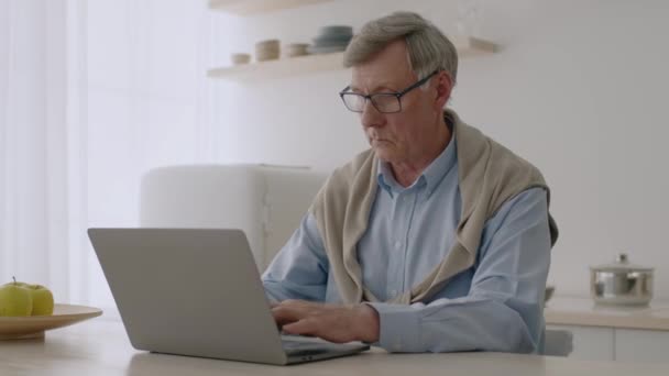 Онлайн-бизнес для всех. Сосредоточенный старший человек печатает на ноутбуке, делая удаленную задачу от интернет-работодателя — стоковое видео