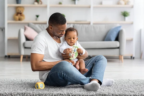 Babalık kavramı. Mutlu siyah adam evde sevimli küçük çocukla oynuyor. — Stok fotoğraf