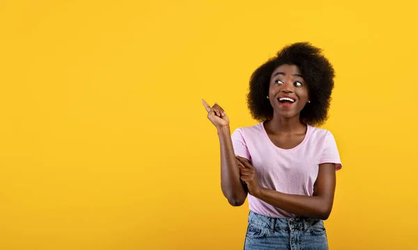 Venta estacional. Emocional dama afroamericana apuntando al espacio en blanco sobre fondo de estudio amarillo, diseño de pancarta — Foto de Stock