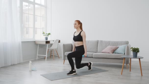 Femme de remise en forme faisant étape se jette tenant haltères exercice à la maison — Video