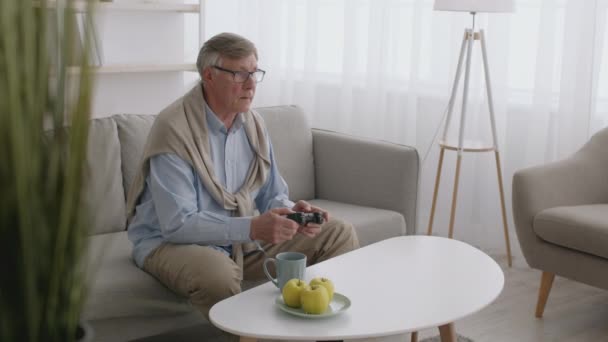 Senior man gamer παίζοντας βιντεοπαιχνίδια με joystick στο σπίτι, χάνοντας και νιώθοντας ενοχλημένος — Αρχείο Βίντεο