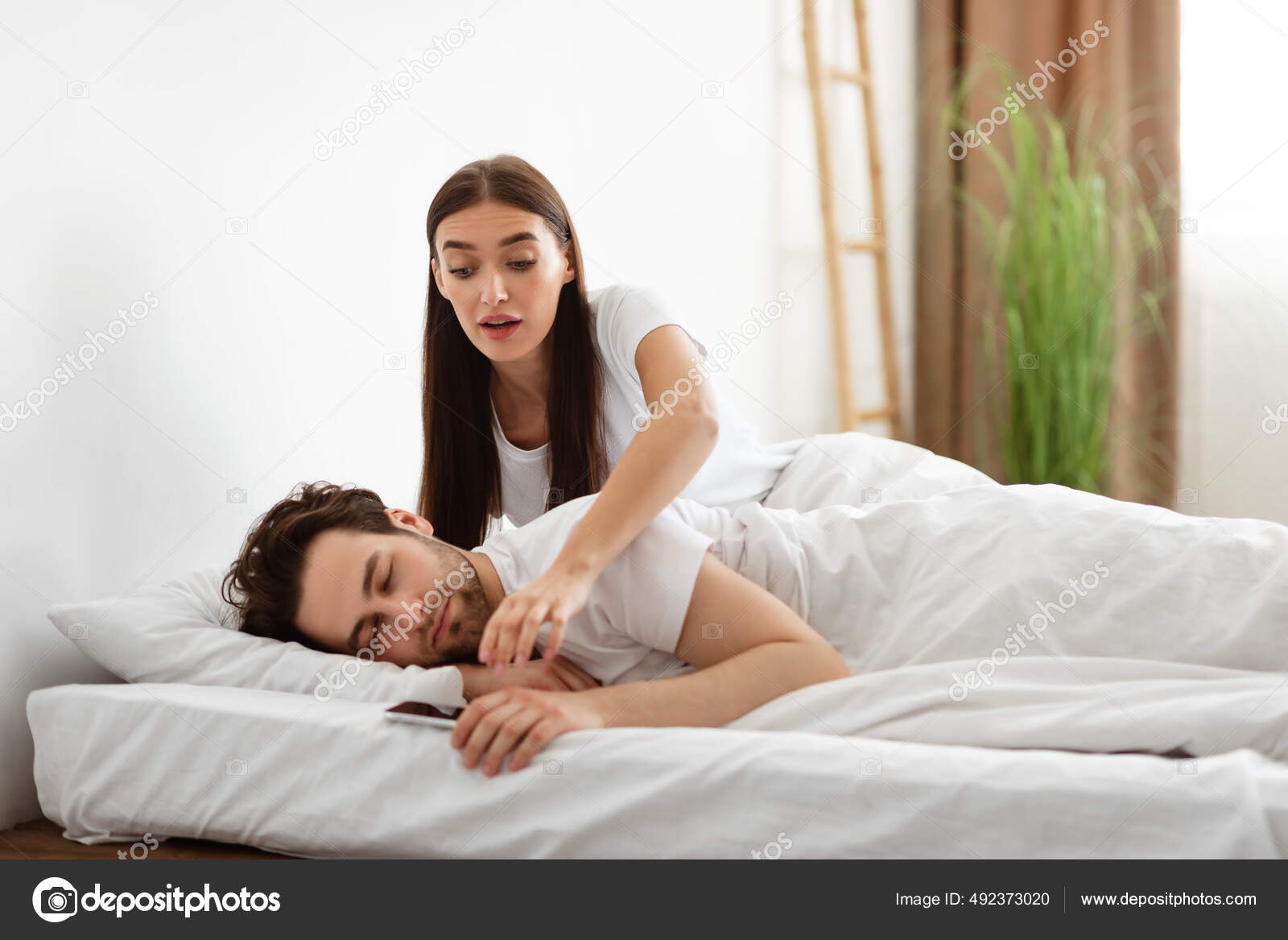 Jealous Woman Taking Husbands Phone While He Sleeps In Bedroom Stock Photo by ©Milkos 492373020