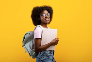 Tecritten sonra öğrenci ya da okula dönmek. Sırt çantası ve not defterleriyle gözlüklü Afro-Amerikan kadın.